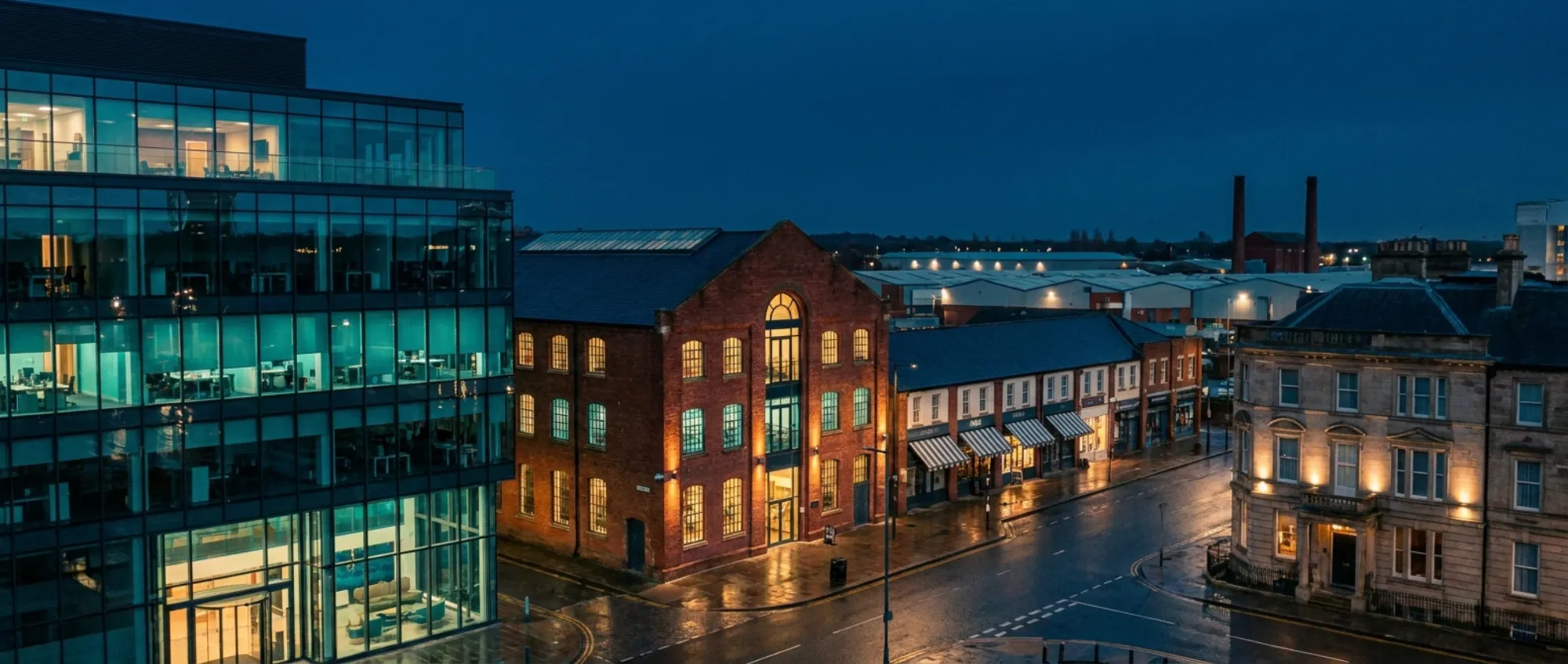 A varied commercial streetscape: offices, warehouse conversion, retail and hotel buildings at dusk